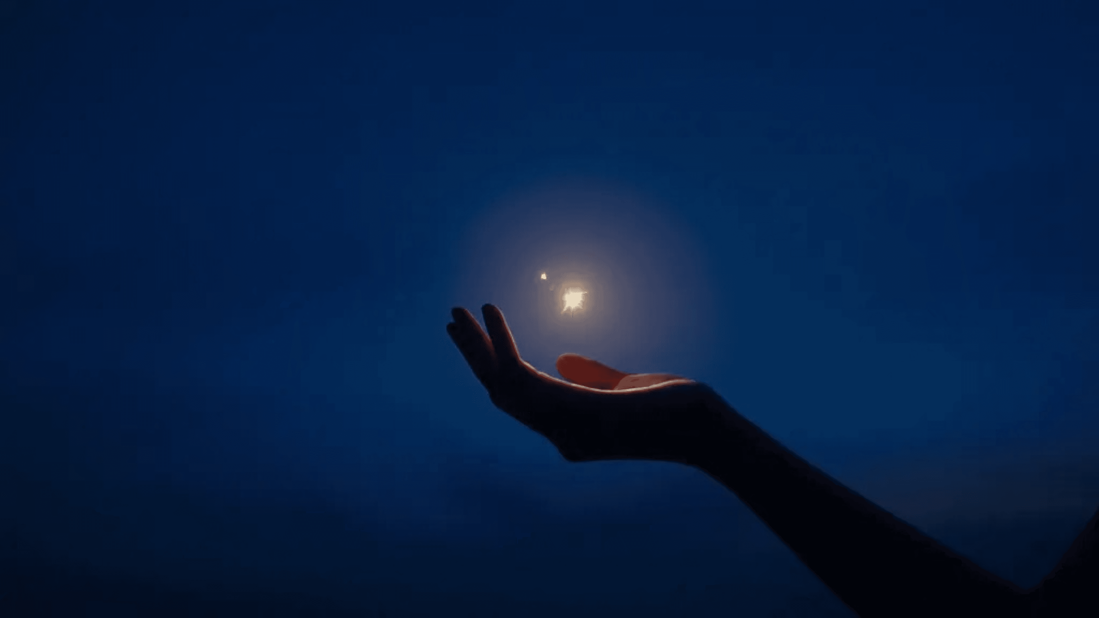 A hand reaching towards a glowing light in a deep blue night sky